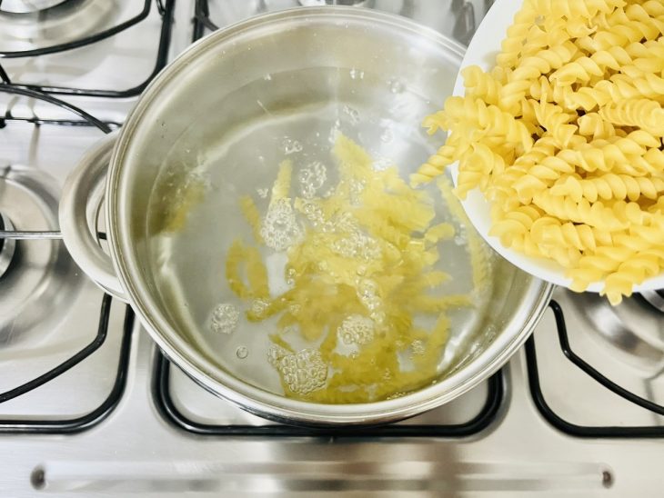 Macarrão cozinhando em água fervente com sal.