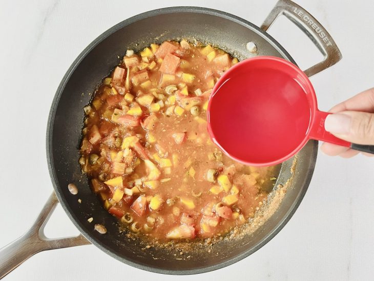 Água do cozimento sendo adicionada ao molho na panela.