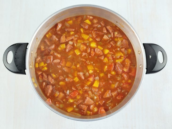 Molho de tomate e temperos sendo adicionados à panela.