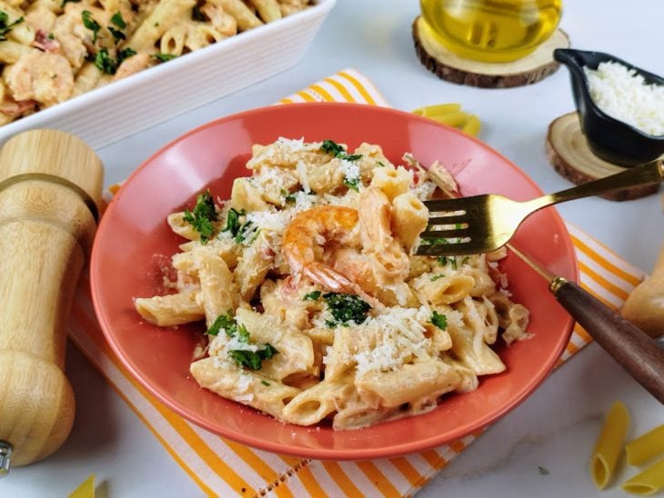 Porção de macarrão cremoso com camarão em um prato.