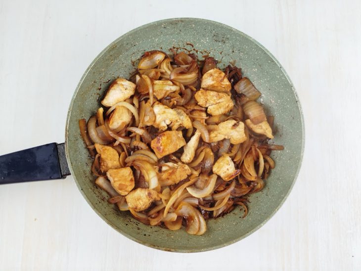 Creme de leite fresco sendo incorporado ao frango, formando um molho claro e uniforme.