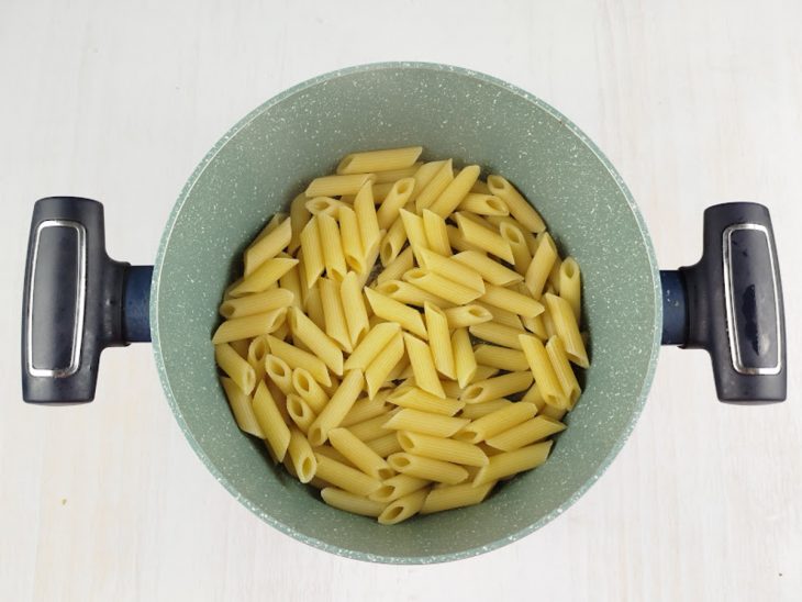 Macarrão penne cozinhando em água fervente com sal.