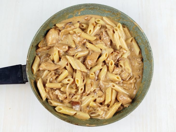 Massa escorrida sendo misturada diretamente ao molho cremoso.