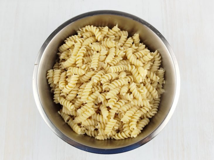 Macarrão cozido numa travessa redonda de inox.