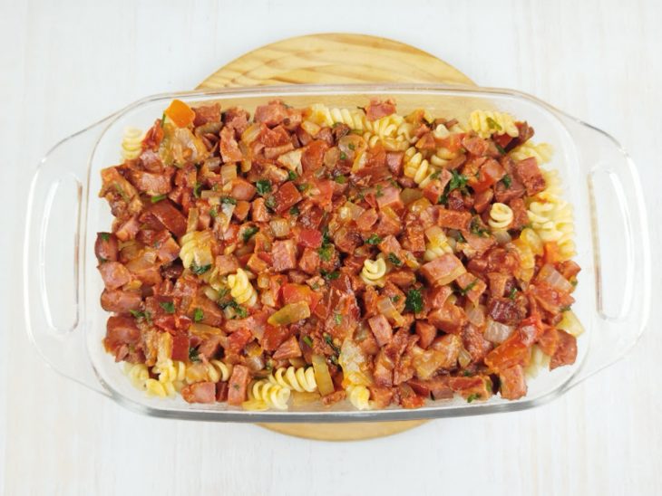 Refratário com camada de molho branco, macarrão e refogado de bacon com calabresa.