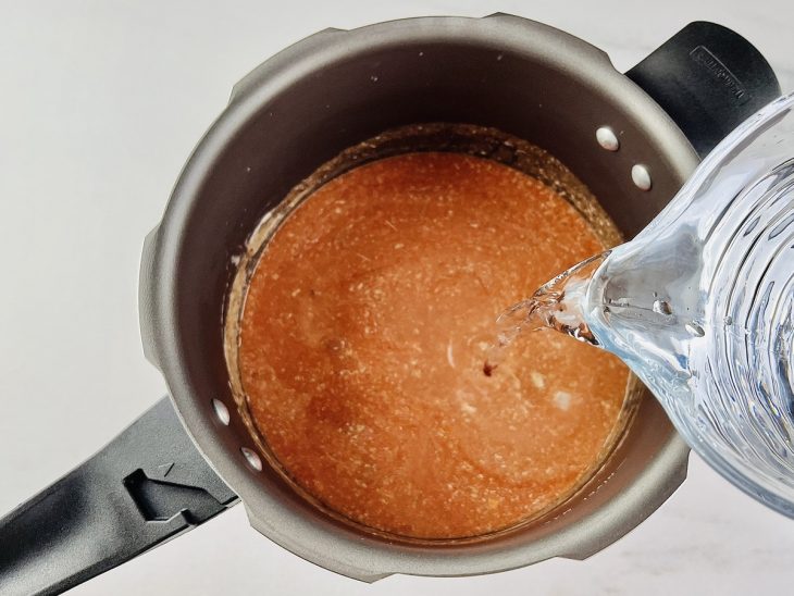 Molho de tomate, sal, creme de leite e água adicionados na panela de pressão.