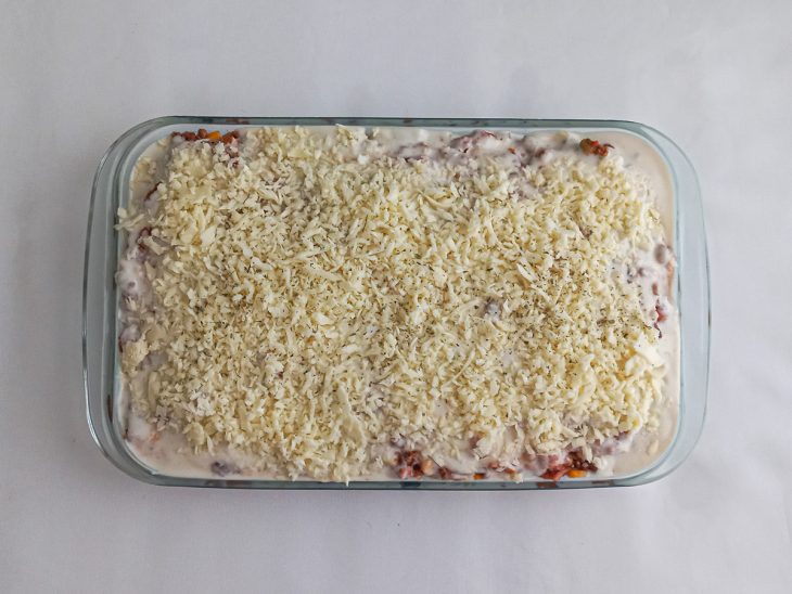 Molho branco e queijo adicionados no refratário sobre a carne moída.