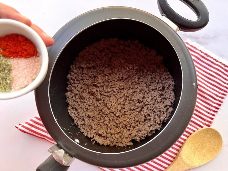 Temperos sendo colocados na carne moída dentro da panela de pressão.