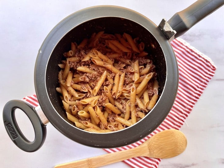 Macarrão cru misturado com o molho e carne na panela de pressão.