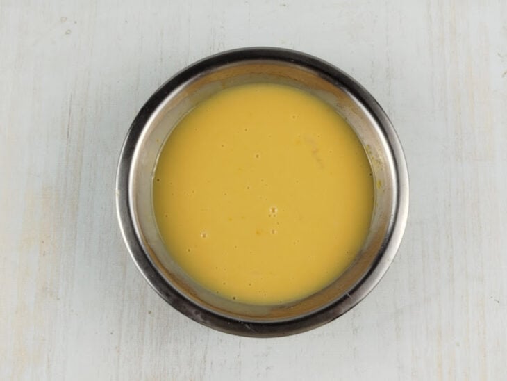 Gemas e leite condensado sendo misturados em uma tigela até formar um creme homogêneo.