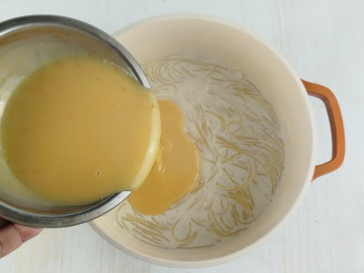 Creme de gemas sendo incorporado ao macarrão cozido na panela com o fogo baixo.