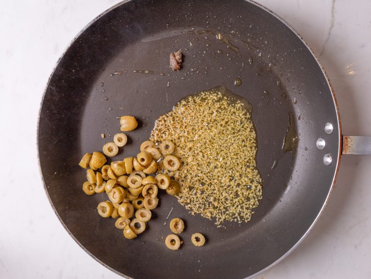 azeitona e anchova adicionada a frigideira para refogar.