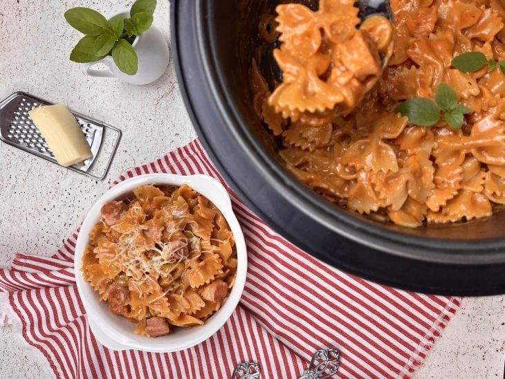 Macarrão feito na panela de pressão com uma porção servida em recipiente ao lado.