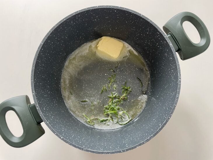 Manteiga derretendo na panela junto com folhas de sálvia para aromatizar.