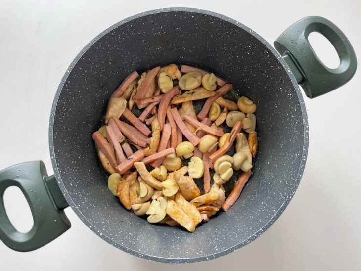 Presunto e champignons sendo adicionados à panela e misturados ao frango.