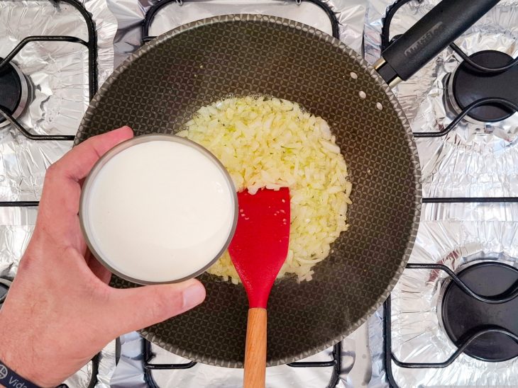 Na frigideira, o alho e a cebola, creme de leite sendo adicionado.