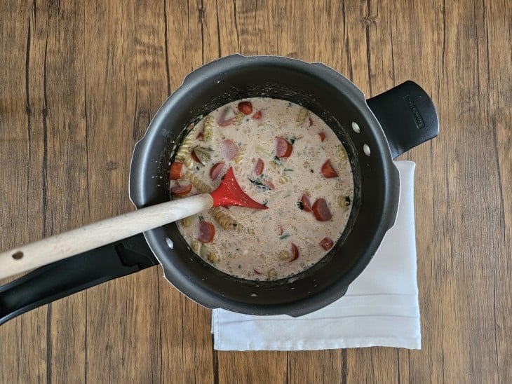 Panela de pressão com ingredientes do macarrão com salsicha.