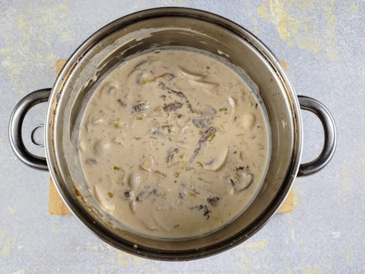 Uma panela com carne, cogumelos e molho ao ponto.