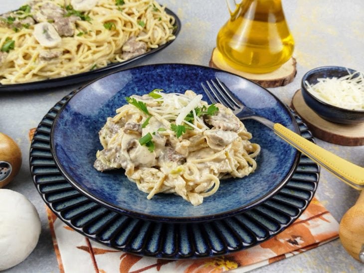 Uma travessa e um prato com macarronada de carne.