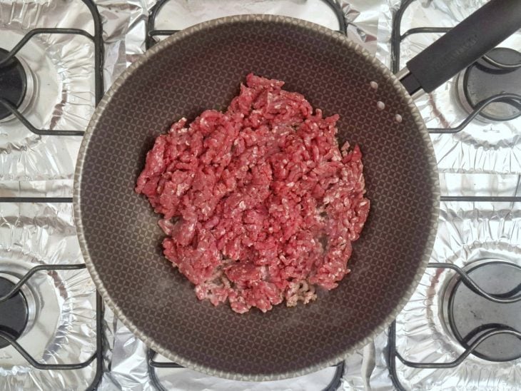 Carne moída refogando em uma frigideira com óleo.
