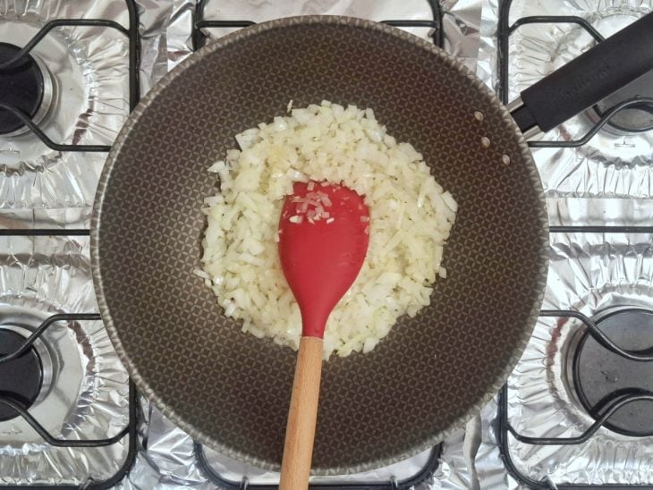 Alho e cebola refogando na frigideira com manteiga.