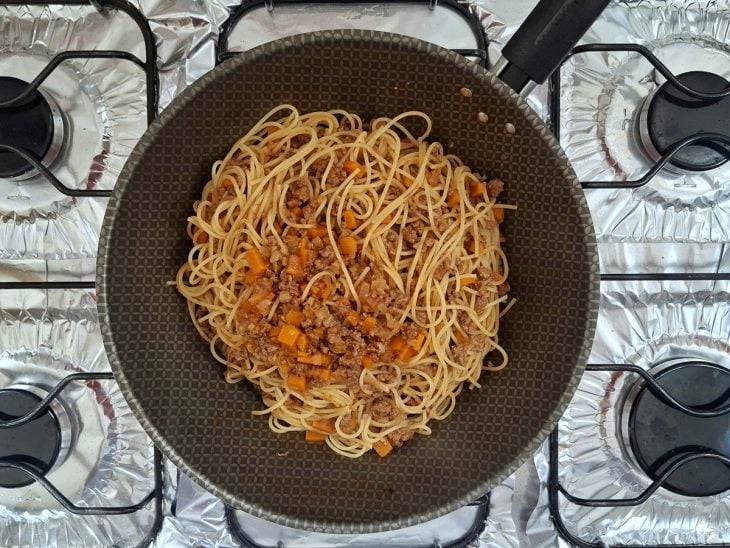 Macarrão adicionado à frigideira com o molho de carne moída.