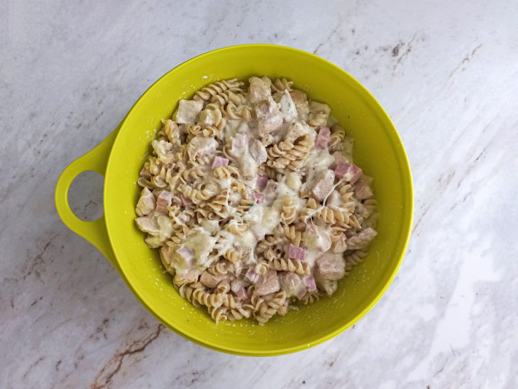 Creme de frango adicionado sobre o macarrão em um recipiente.