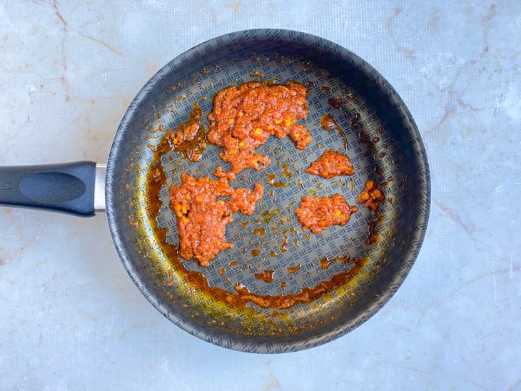 Colorau e extrato de tomate adicionados na frigideira.