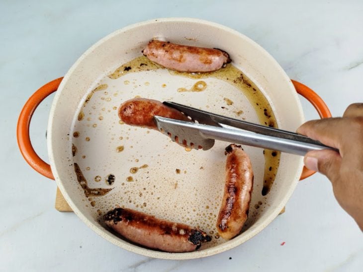 Gomos de linguiça grelhados em uma panela.