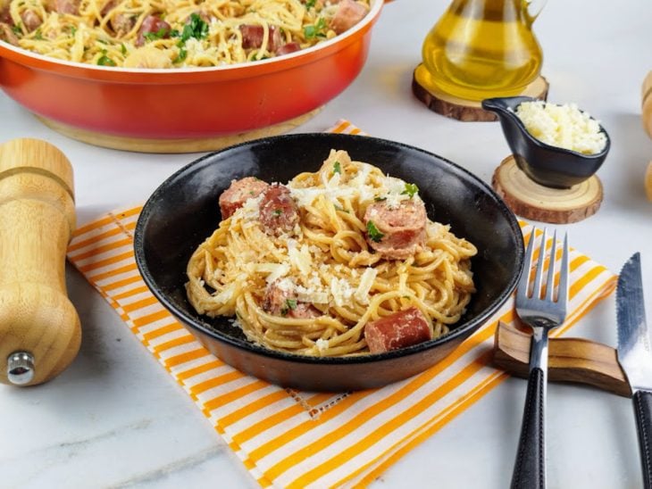 Porção individual de macarronada simples pronta para consumo e finalizada com queijo parmesão ralado.