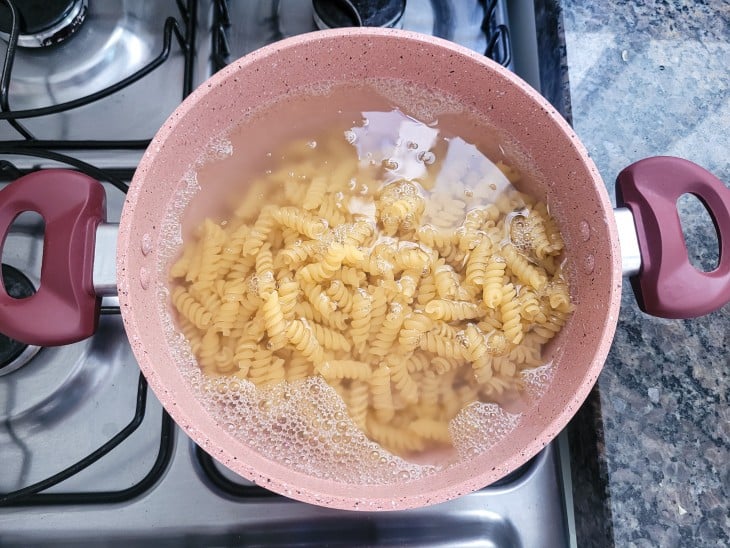 Uma panela contendo macarrão sendo cozido na água fervente.