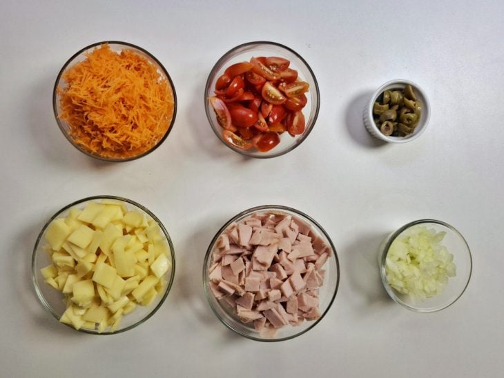 Tomates, presunto, mussarela, azeitona e cebola picados e cenoura ralada.