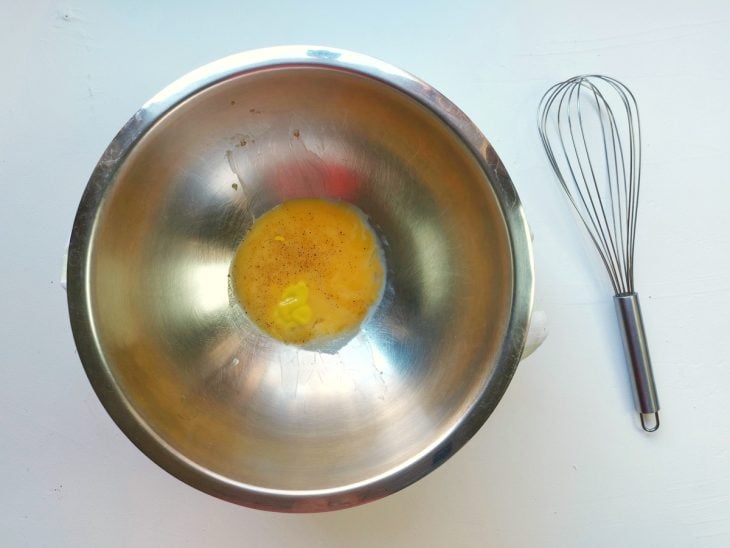 Um fouet e uma tigela com gemas, mostarda, suco de limão, pimenta-do-reino e sal.