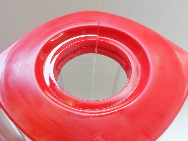 Fio de olho sendo adicionado dentro do liquidificador pela abertura da tampa de cor vermelha