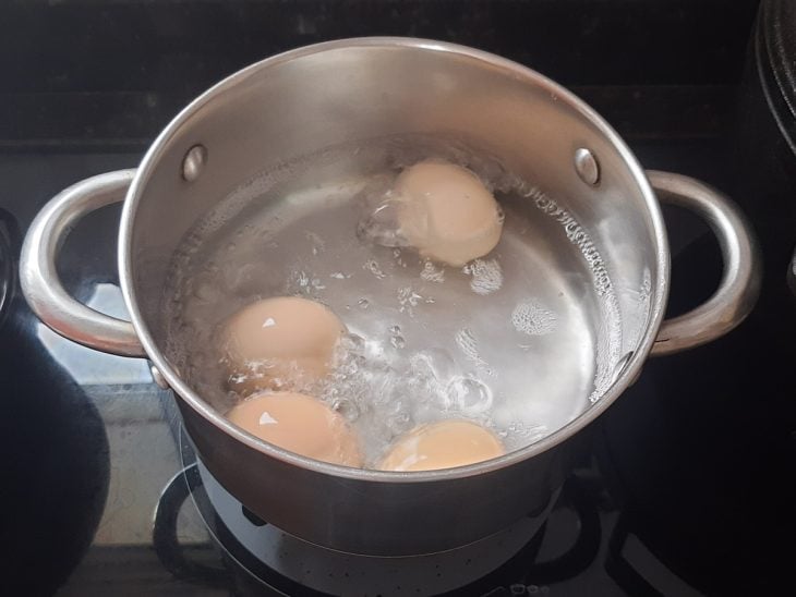 Uma panela com água cozinhando ovos.