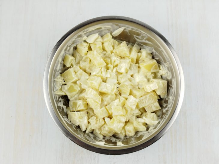 Batatas, cebola e as gemas misturadas numa tigela.