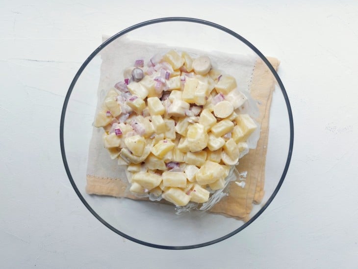 Um recipiente contendo maionese de batata com palmito.