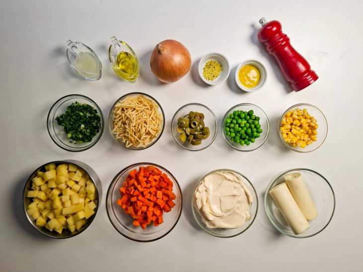 Ingredientes organizados na bancada com batatas e cenouras descascadas e cortadas.