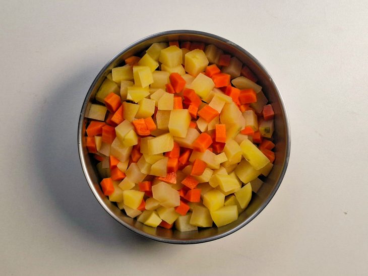 Legumes cozidos sendo transferidos para uma tigela com água gelada.