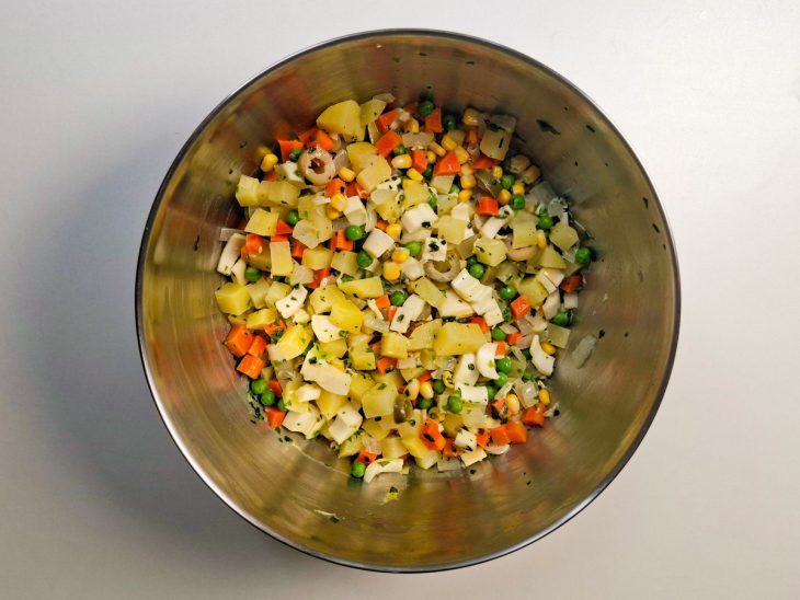 Temperos sendo adicionados à mistura de legumes na tigela.