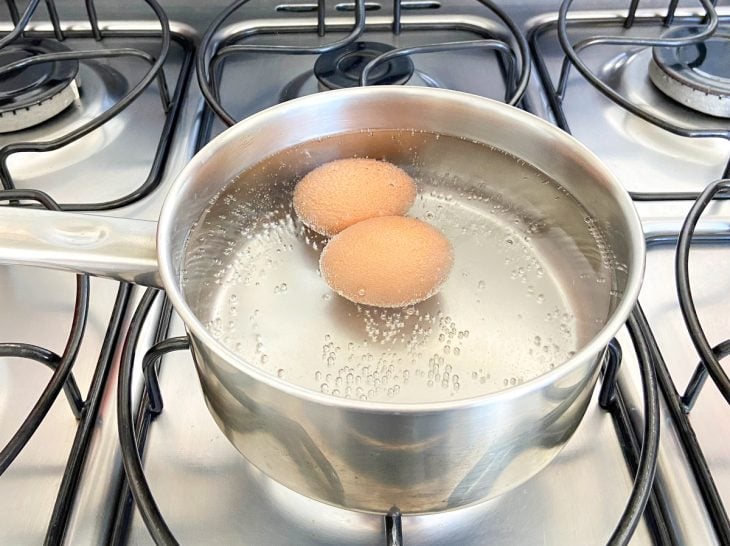 Uma panela com água cozinhando dois ovos.