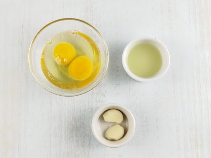 Ovos, alho e óleo separados em recipientes distintos.