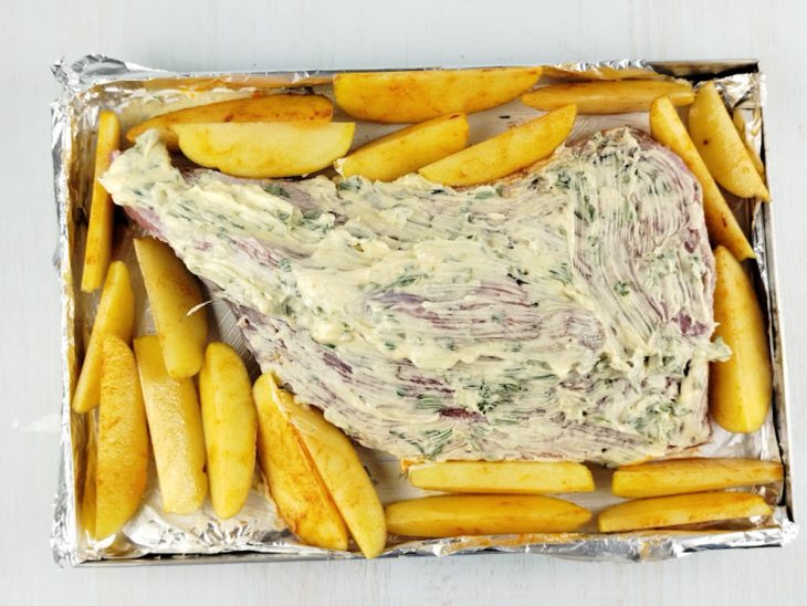 Maminha e batatas distribuídas numa assadeira forrada com papel alumínio.