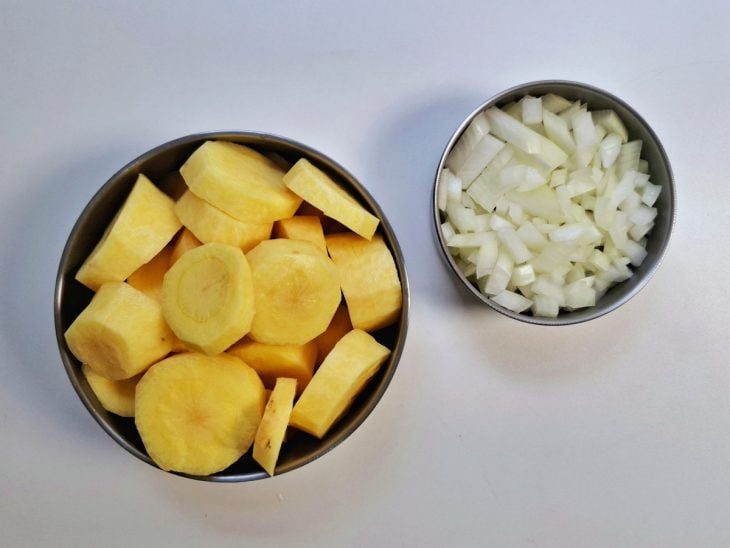Recipientes com cebola e mandioquinhas picadas.