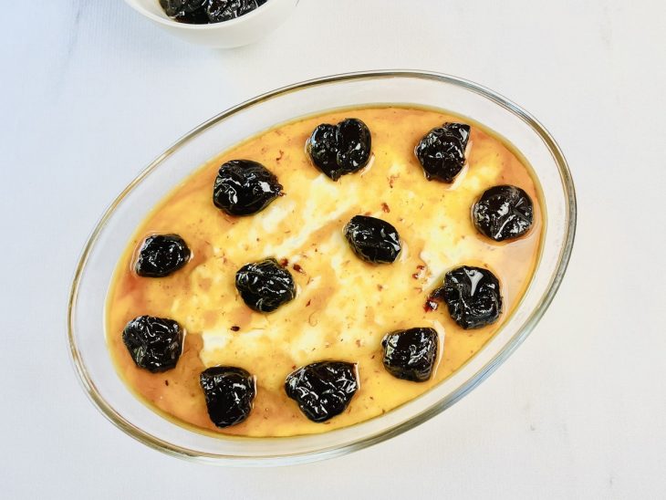 Calda despejada e ameixas acomodadas sobre o manjar.