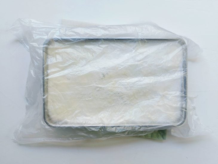 Uma forma com maria-mole coberta por um saco plástico.