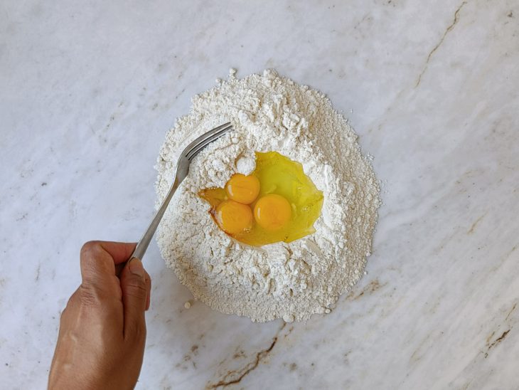 Farinha disposta em formato de vulcão com os ovos no centro.