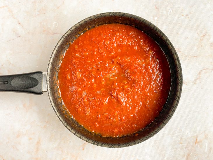 Passata de tomate e água do cozimento colocada na frigideira.