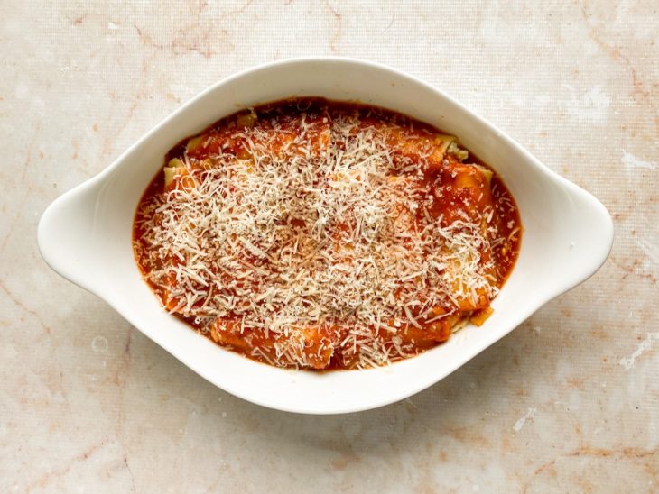 Canelones acomodados no refratário cobertos por passata de tomate e queijo parmesão ralado.