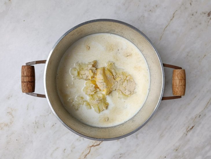 Leite, margarina, sal e caldo da galinha adicionados na panela com batatas amassadas.